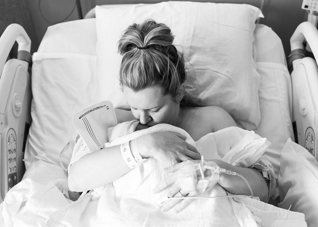 mom kissing newborn baby boy in raleigh hospital
