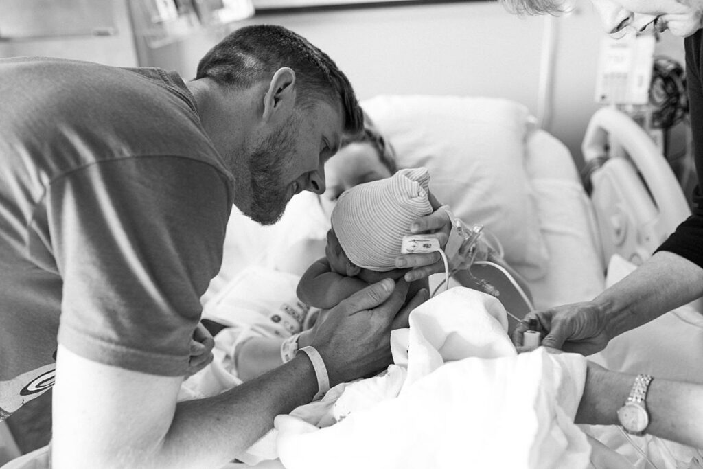 dad holding newborn baby boy in hospital bed