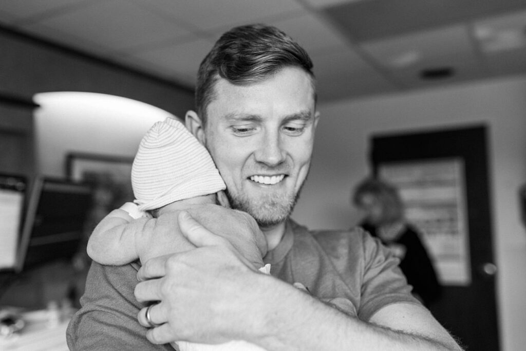 proud dad holding newborn baby boy in hospital