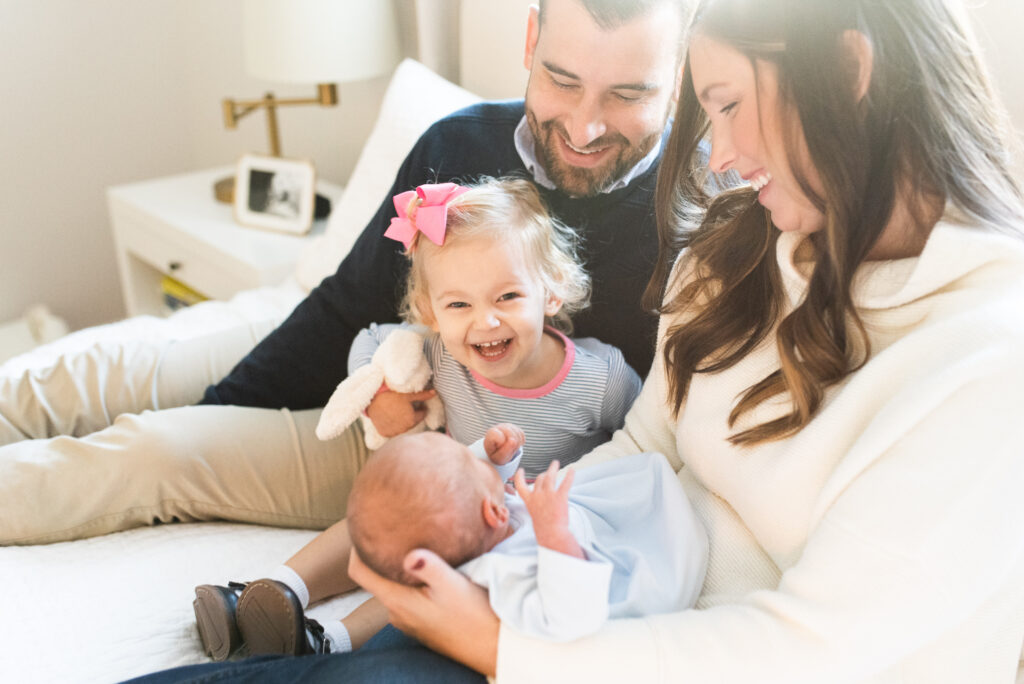 family with newborn baby, big sister smiling at new brother