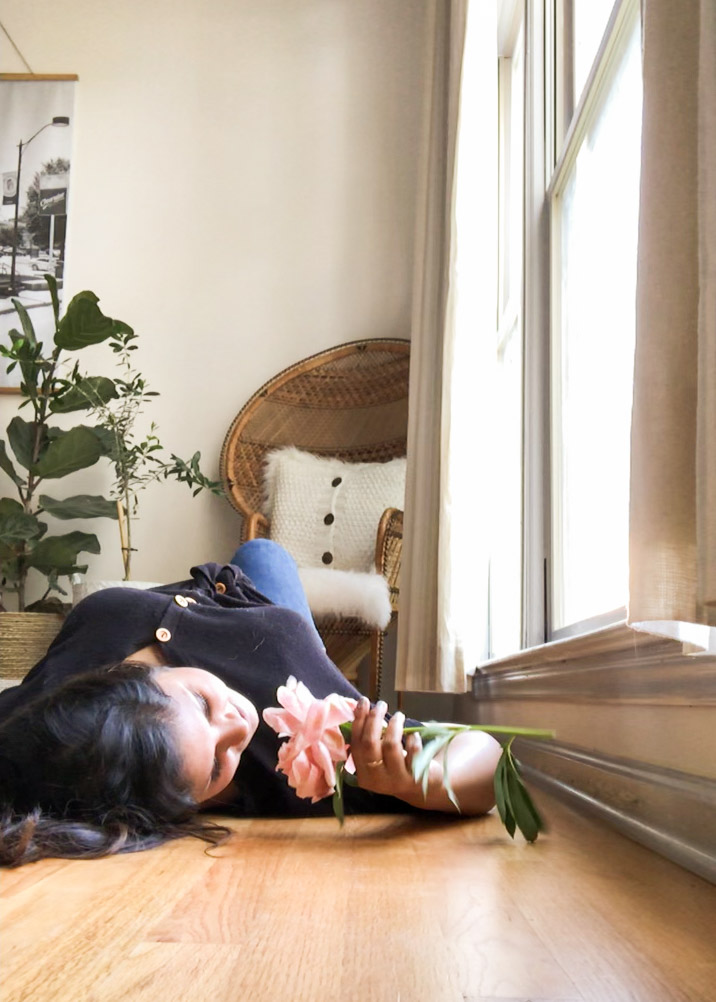 Woman lying on floor smelling flower, virtual sessions via FaceTime