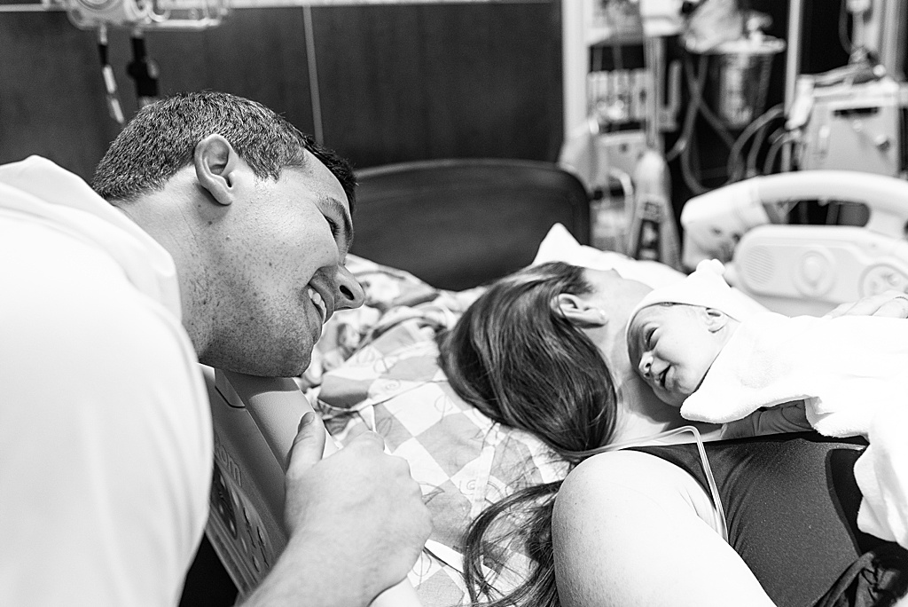 dad looking at newborn baby girl in hospital